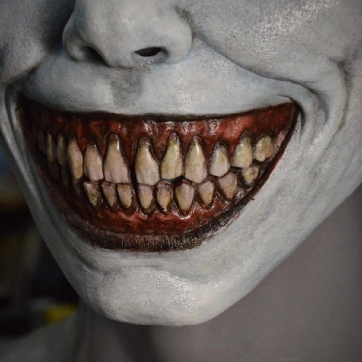 White demon mask close-up showing exaggerated grinning mouth with sharp teeth | Chaps London
