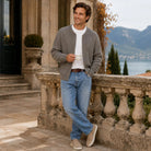 Man wearing gray knit cardigan with jeans, standing on terrace balcony | Chaps London