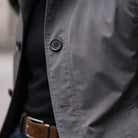 Gray cotton rain mac button detail worn by person, close-up view | Chaps London