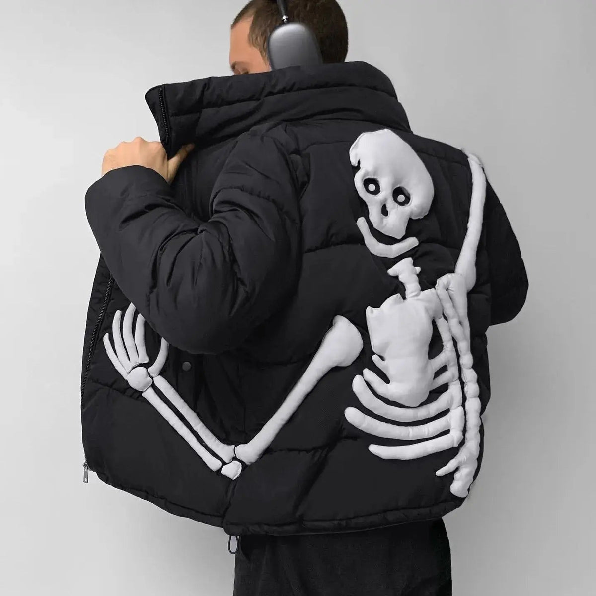 Black puffer jacket with raised white skeleton design worn by man | Chaps London