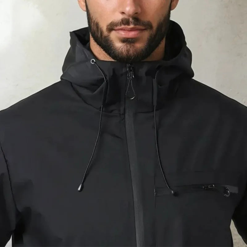 Black hooded rain jacket with zip pocket worn by man, close-up view | Chaps London
