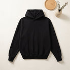 Black hoodie laid flat beside wooden tray and plant | Chaps London