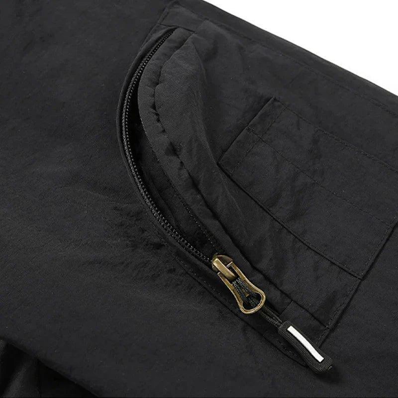 Black utility jacket close-up showing zippered sleeve pocket with brass zipper hardware | Chaps London