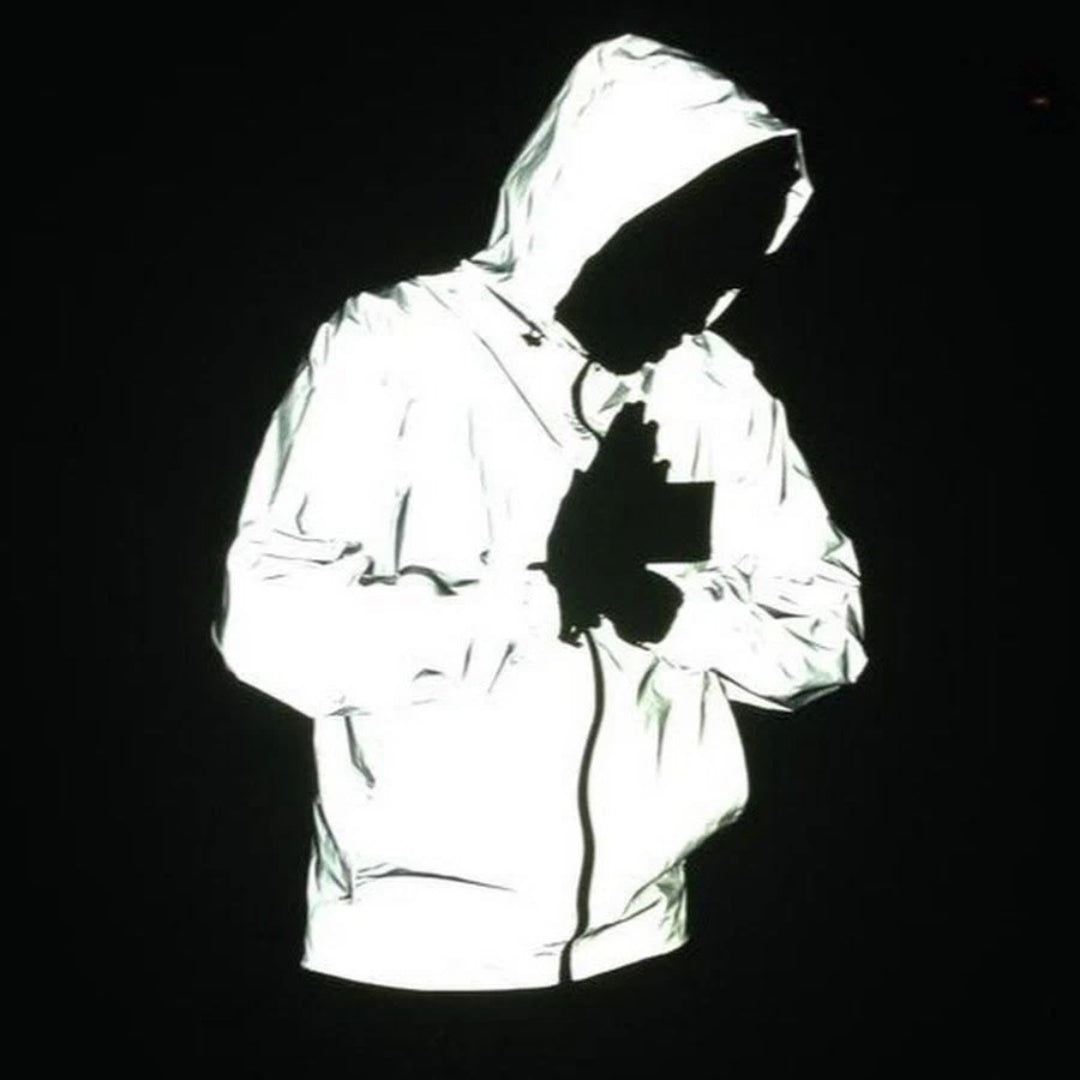 Reflective silver hooded jacket worn by person, glowing against black background | Chaps London