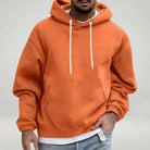Man wearing orange hooded sweatshirt with white drawstrings, layered white shirt underneath | Chaps London