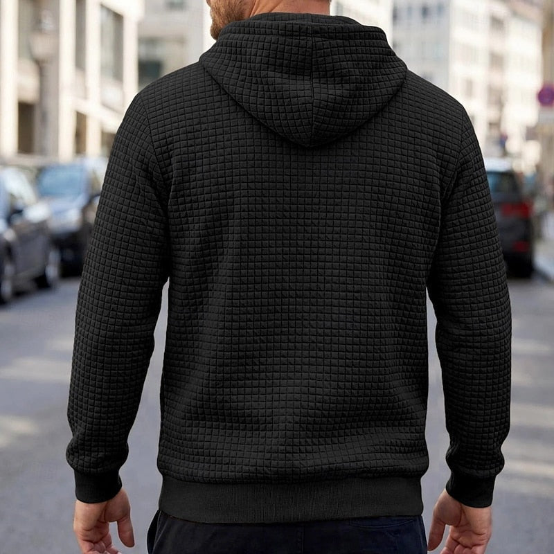 Black textured quilted hoodie worn by man, back view, outdoor street setting | Chaps London