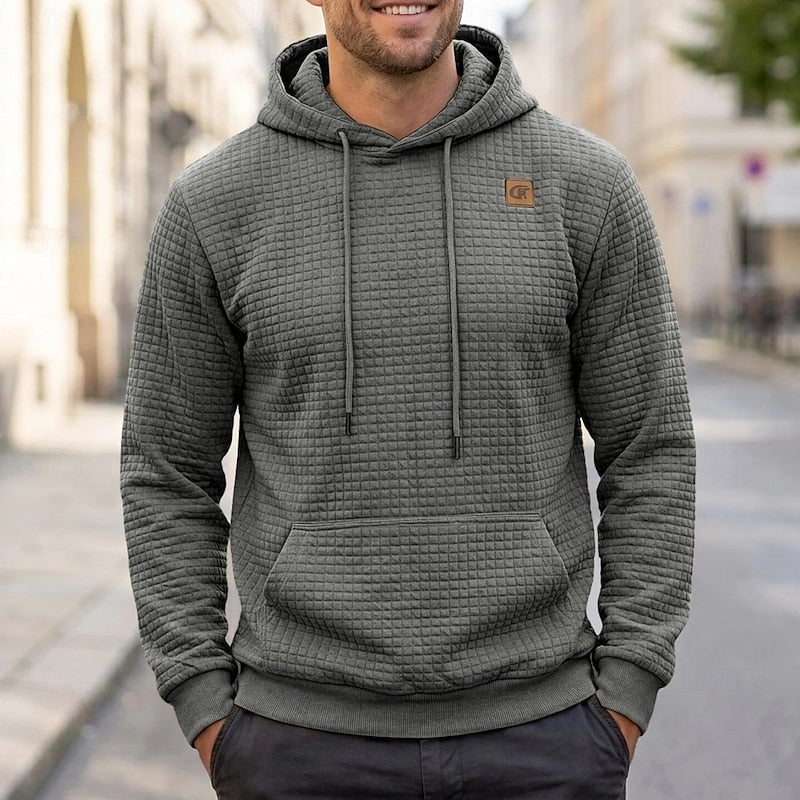 Man wearing grey quilted texture hoodie with chest patch, street background | Chaps London