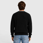 Man wearing black ribbed knit crewneck sweater, rear view, with blue jeans | Chaps London