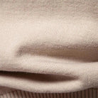 Close-up of beige knitted fabric with ribbed texture and folded draping | Chaps London