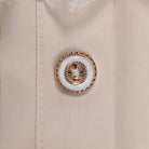 Close-up of beige shirt with ornate gold and white decorative button | Chaps London