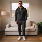Man wearing black half-zip tracksuit with joggers, standing in living room | Chaps London