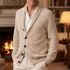Man wearing beige ribbed knit shawl collar cardigan with buttons, fireplace background | Chaps London