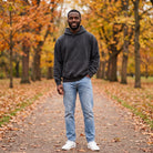 Man wearing charcoal grey oversized hoodie, standing on autumn park path | Chaps London