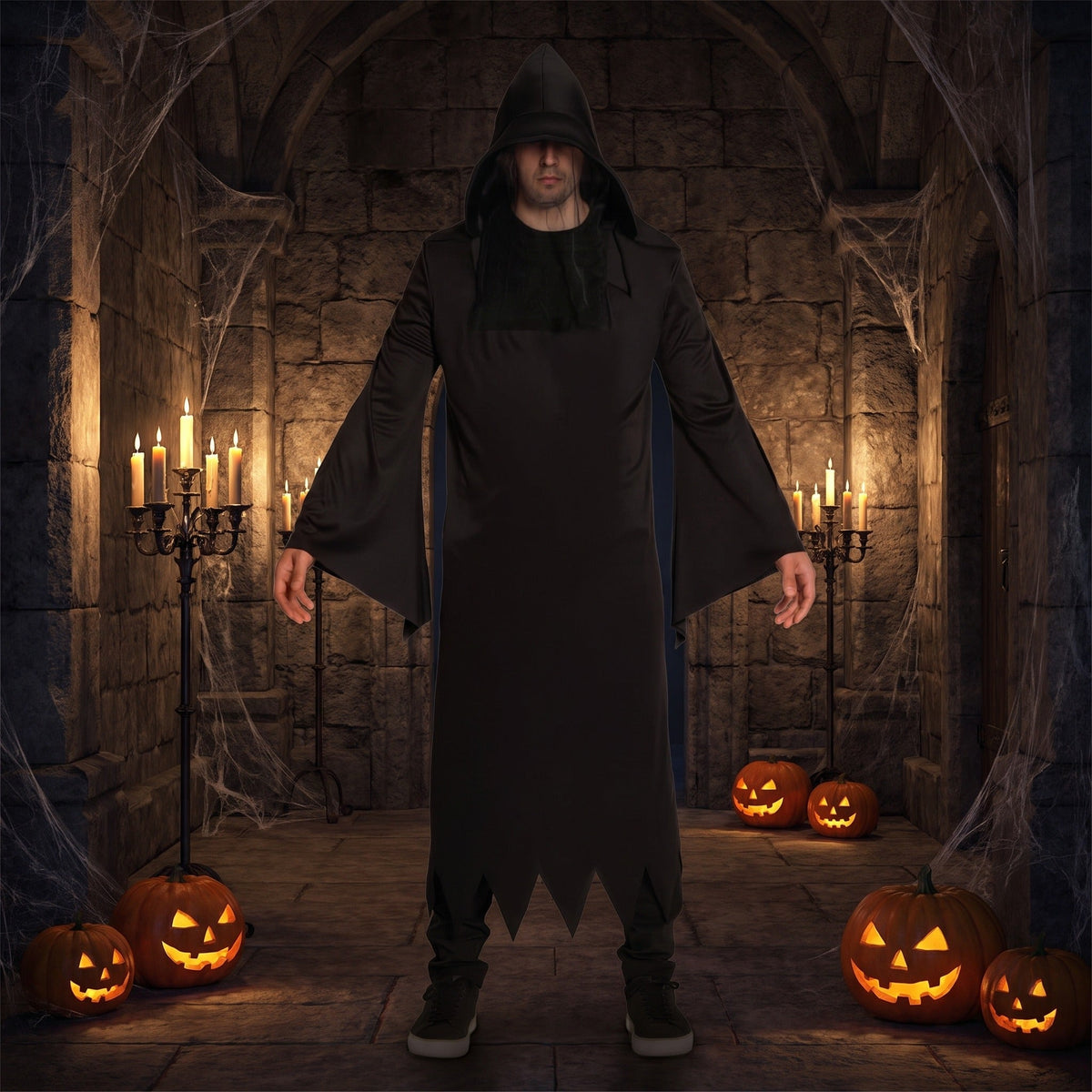 Man wearing black hooded grim reaper robe standing among Halloween pumpkins | Chaps London