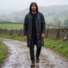 Man wearing black hooded raincoat, walking on rural path, worn outdoors | Chaps London