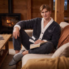 Man wearing dark gray fleece pajama set, sitting on couch indoors | Chaps London