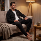 Man wearing black zip hoodie and joggers, sitting on couch | Chaps London