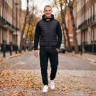 Man wearing black quilted hooded jacket and matching joggers on street | Chaps London