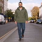Man wearing olive green hooded jacket with jeans, walking on street | Chaps London