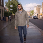 Man wearing olive green hooded rain jacket walking on city street | Chaps London