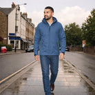 Man wearing blue hooded waterproof jacket with jeans, walking on street | Chaps London