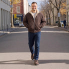 Man wearing brown sherpa lined jacket with jeans, walking on city street | Chaps London