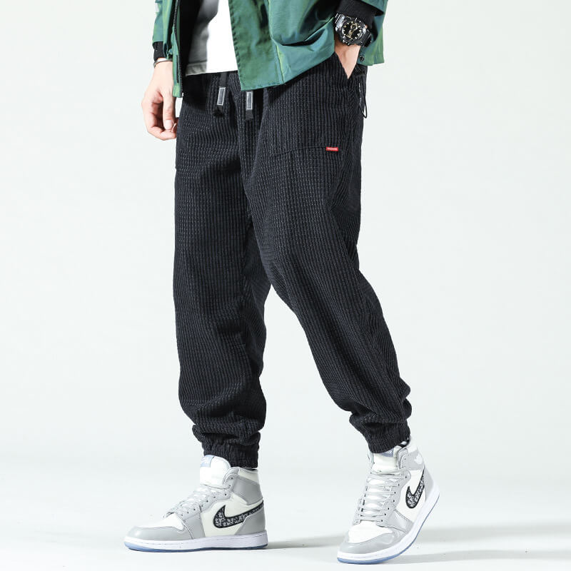 Black corduroy trousers with a drawstring waist and cuffed ankles