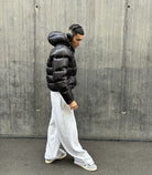 Black high-shine hooded puffer jacket, side view