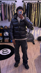Black shiny hooded puffer jacket zipped up, mirror photo