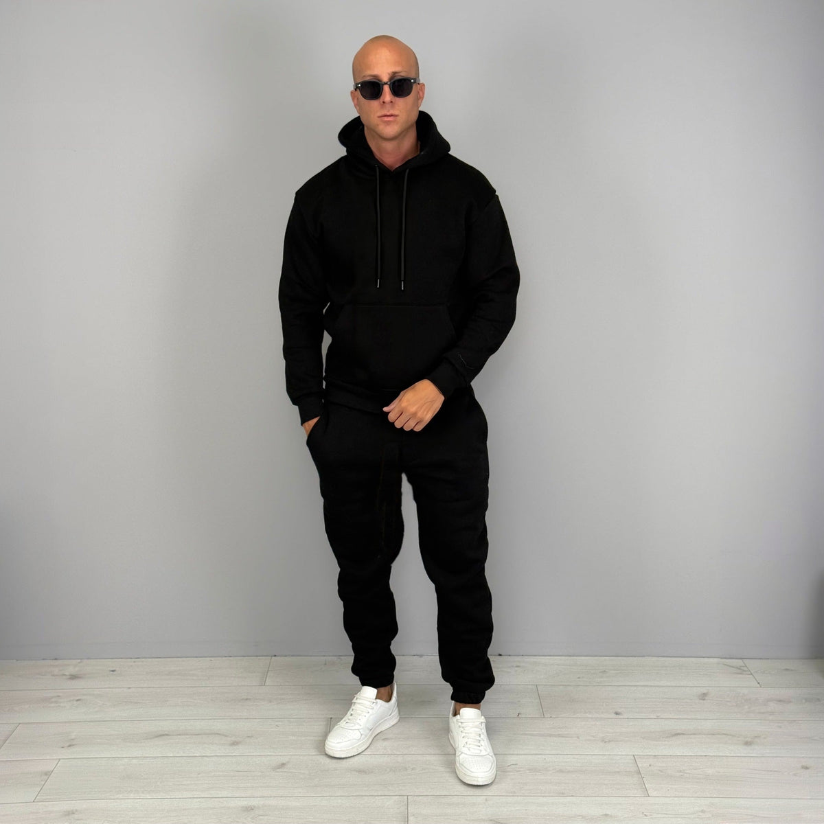 Man wearing black hoodie tracksuit with cuffed joggers and white sneakers | Chaps London