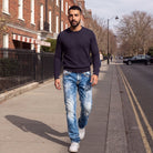 Man walking on a London street in blue acid wash straight leg jeans with contrast stitching and a navy jumper