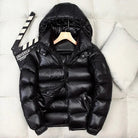 Black shiny hooded puffer jacket on hanger, displayed against pillows | Chaps London
