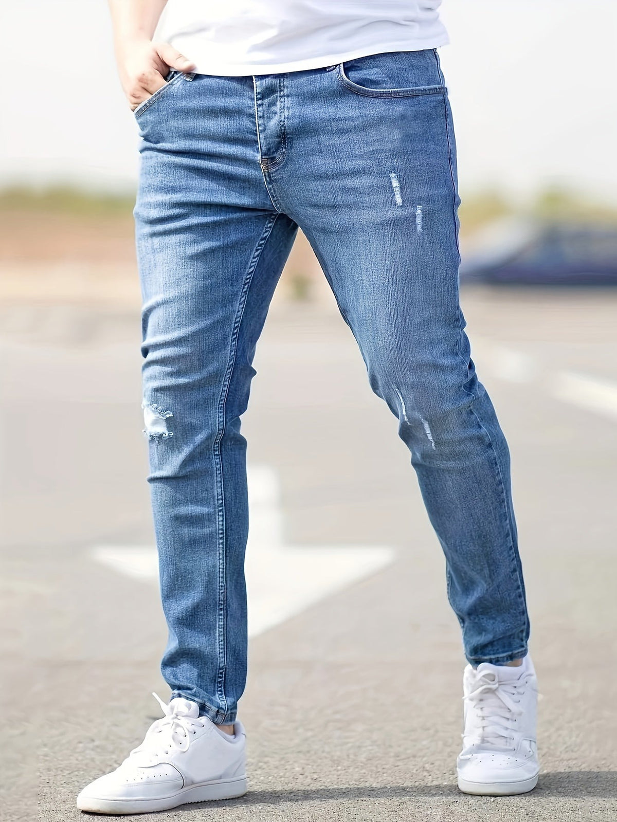 Man wearing blue distressed skinny jeans with white sneakers, outdoor setting | Chaps London