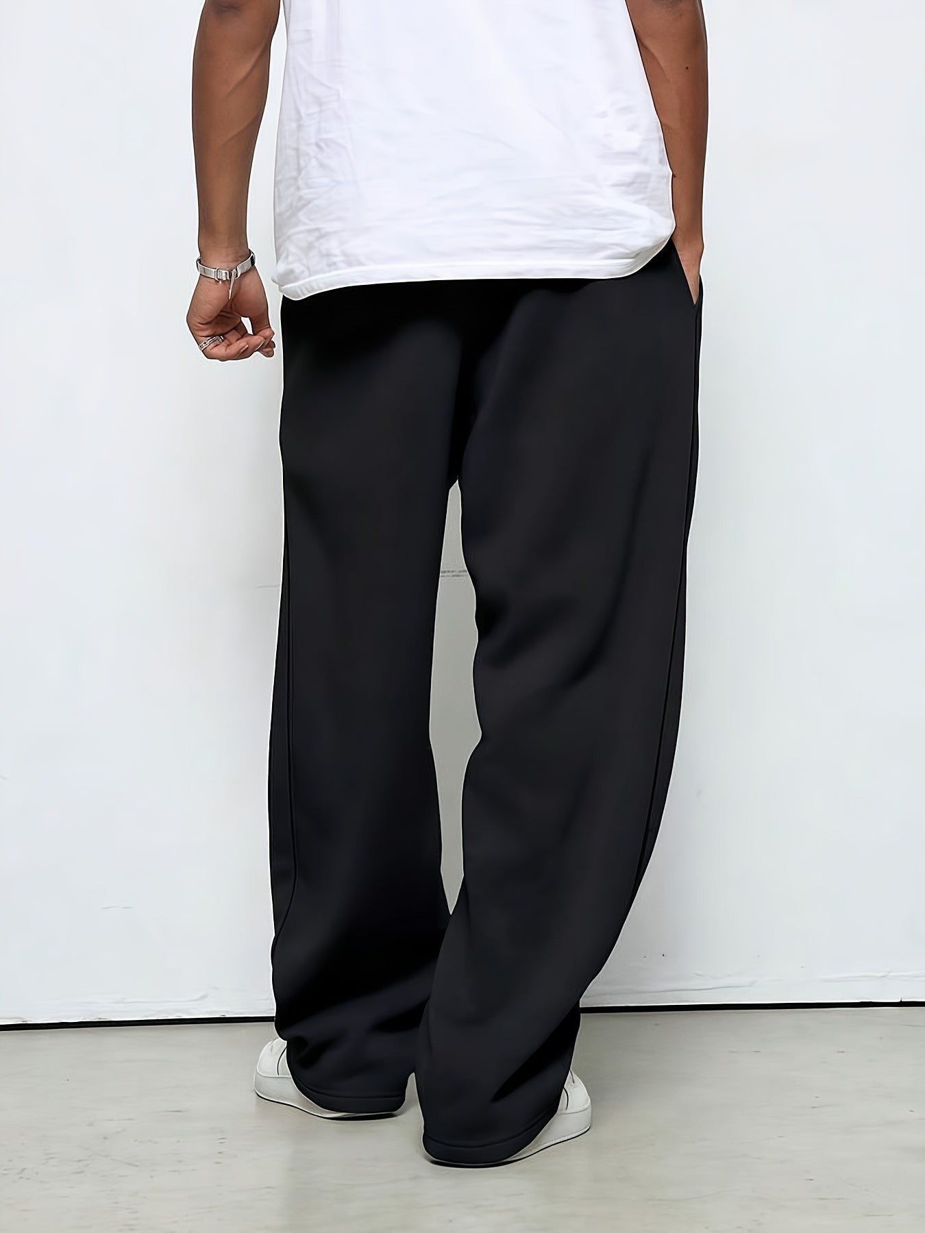 Man wearing black straight-leg baggy joggers, white sneakers, rear view | Chaps London