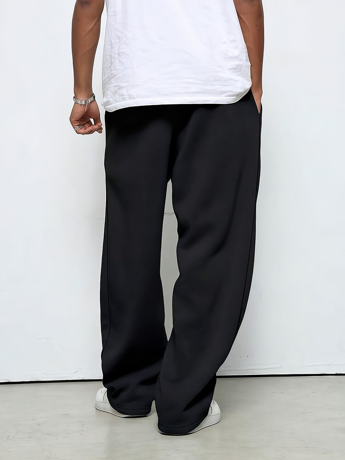 Man wearing black straight-leg baggy joggers, white sneakers, rear view | Chaps London