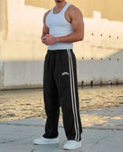 Men's black side-stripe tracksuit bottoms worn outdoors