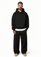 Man wearing black oversized hoodie and straight-leg joggers, tan shoes visible | Chaps London