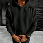 Black plain hoodie with kangaroo pocket worn by man outdoors | Chaps London