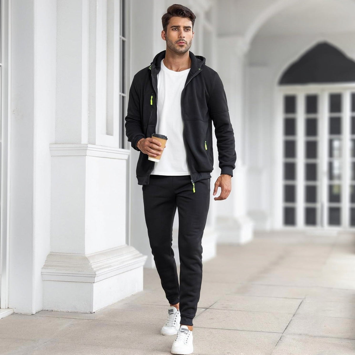 Man wearing black zip hoodie and matching joggers with white sneakers outdoors | Chaps London
