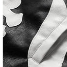 Close-up of black faux leather jacket with white bone applique detail | Chaps London