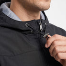Man wearing black hooded jacket, adjusting drawstring toggle at neckline closeup | Chaps London