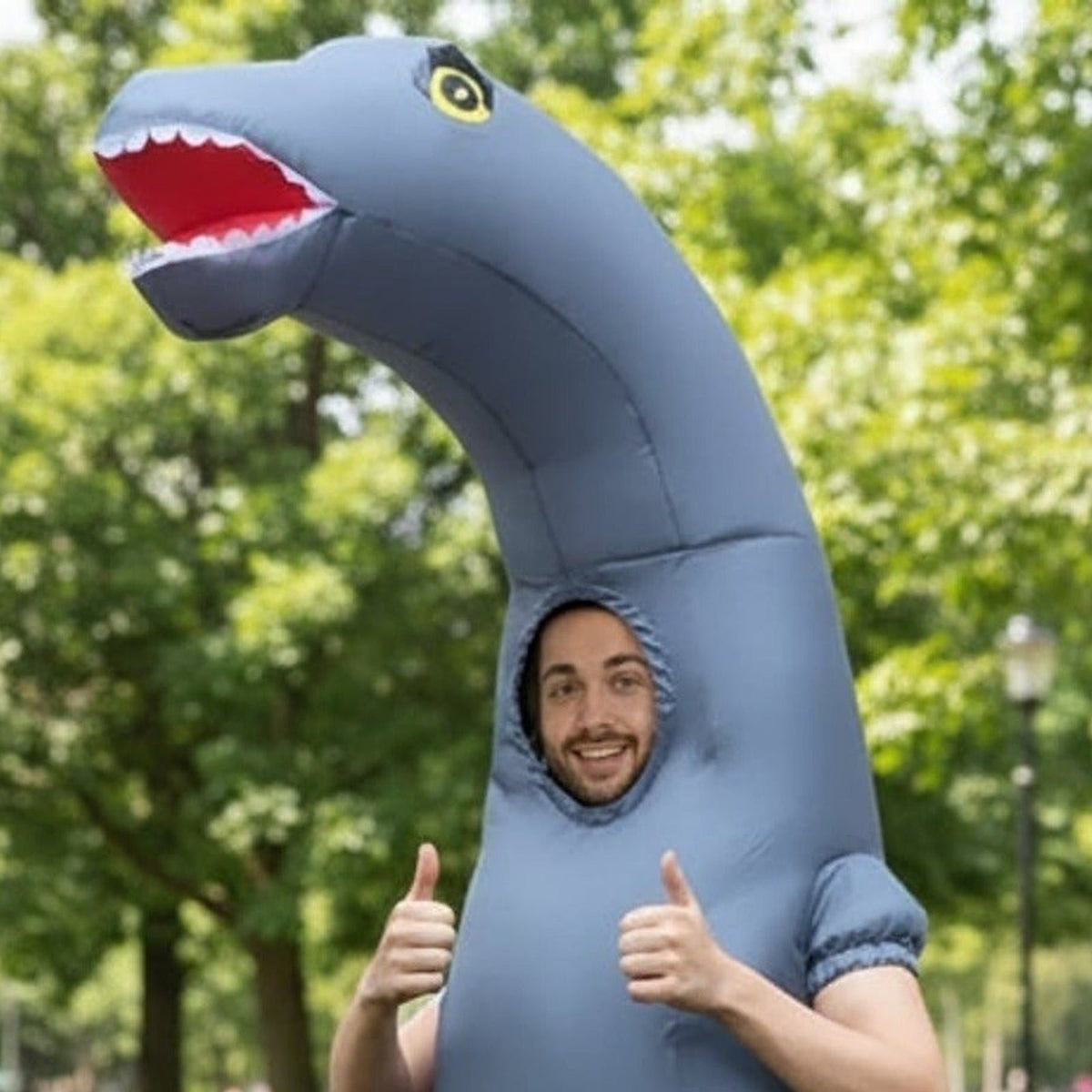 Man wearing gray inflatable long-neck dinosaur costume, giving thumbs up outdoors | Chaps London