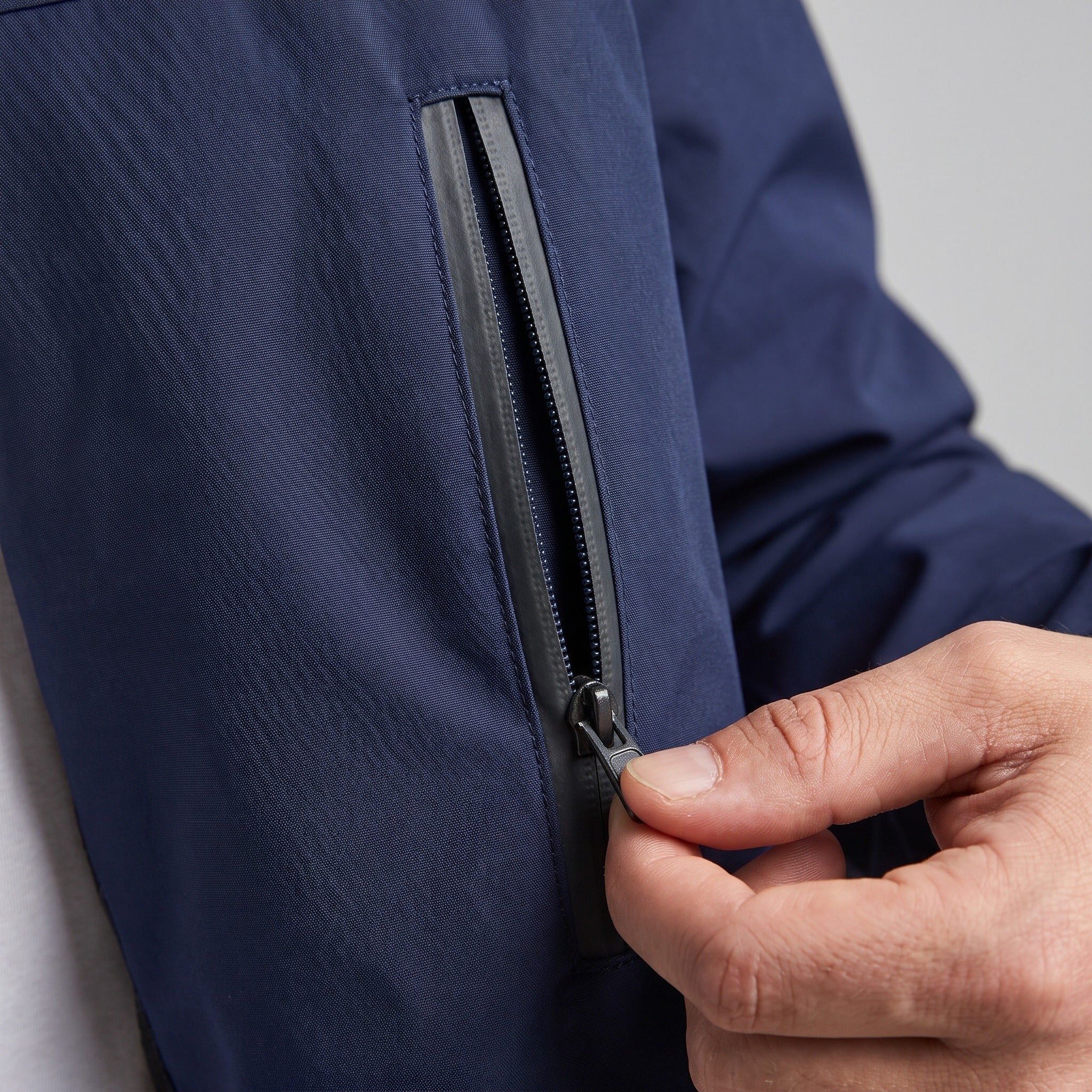 Close-up of navy windbreaker zip pocket, worn by a person | Chaps London