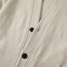 Close-up of beige textured cardigan jacket with navy buttons, worn by person | Chaps London