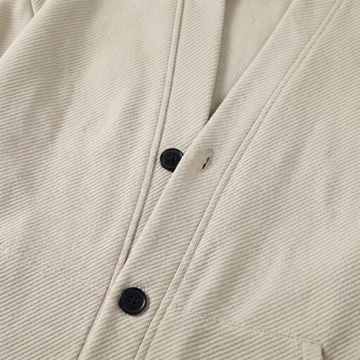 Close-up of beige textured cardigan jacket with navy buttons, worn by person | Chaps London