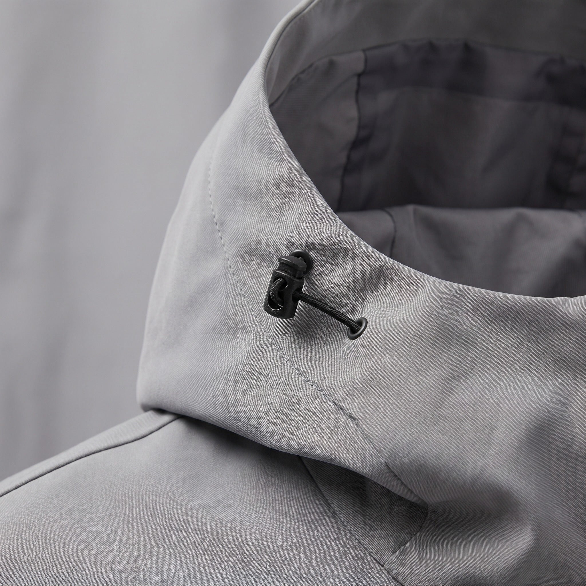 Gray rain jacket close-up showing hood collar and toggle drawstring detail | Chaps London