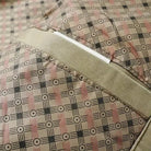 Beige plaid fabric close-up with fold and zipper detail, flat lay | Chaps London