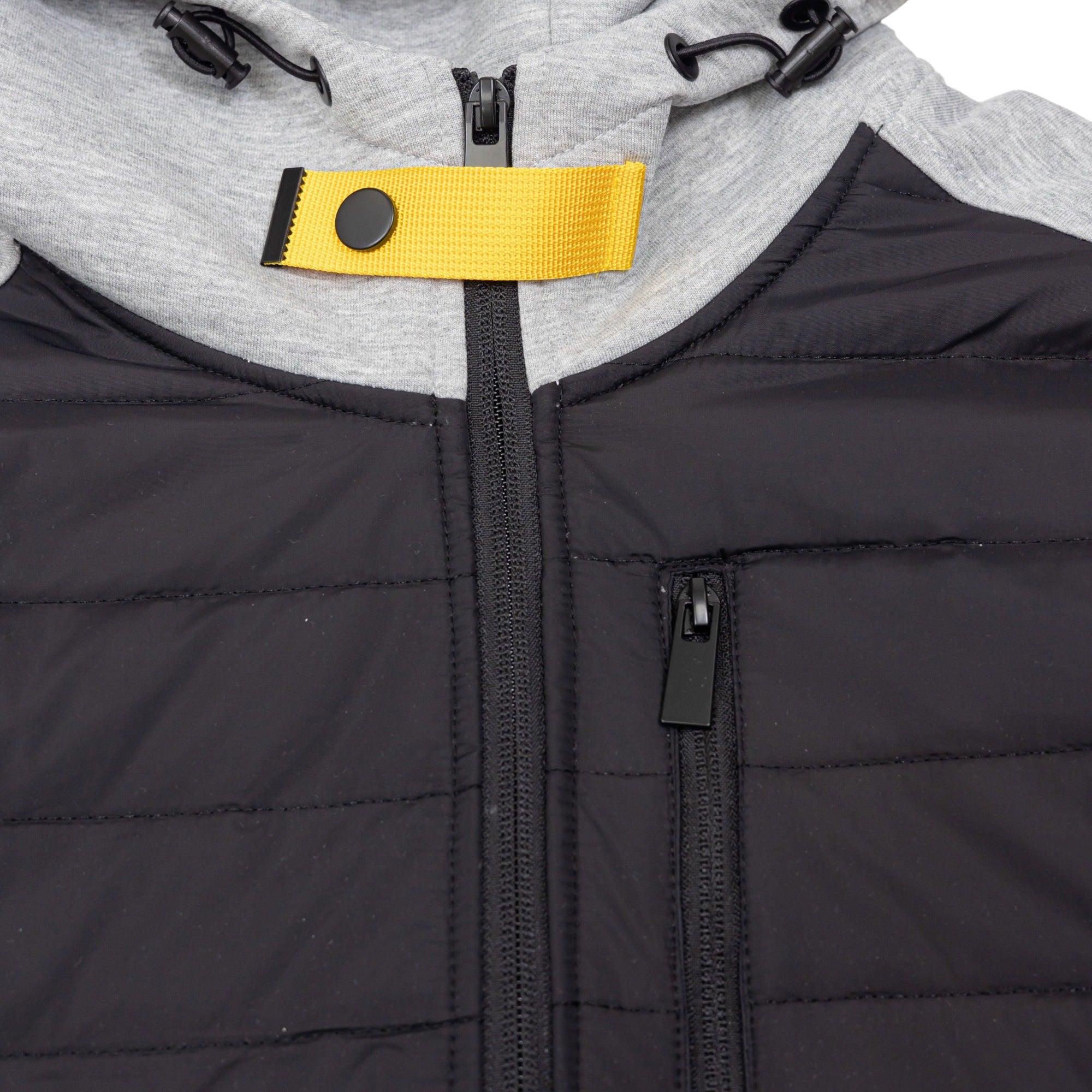 Close-up of black quilted jacket with grey hood and yellow zipper pull | Chaps London