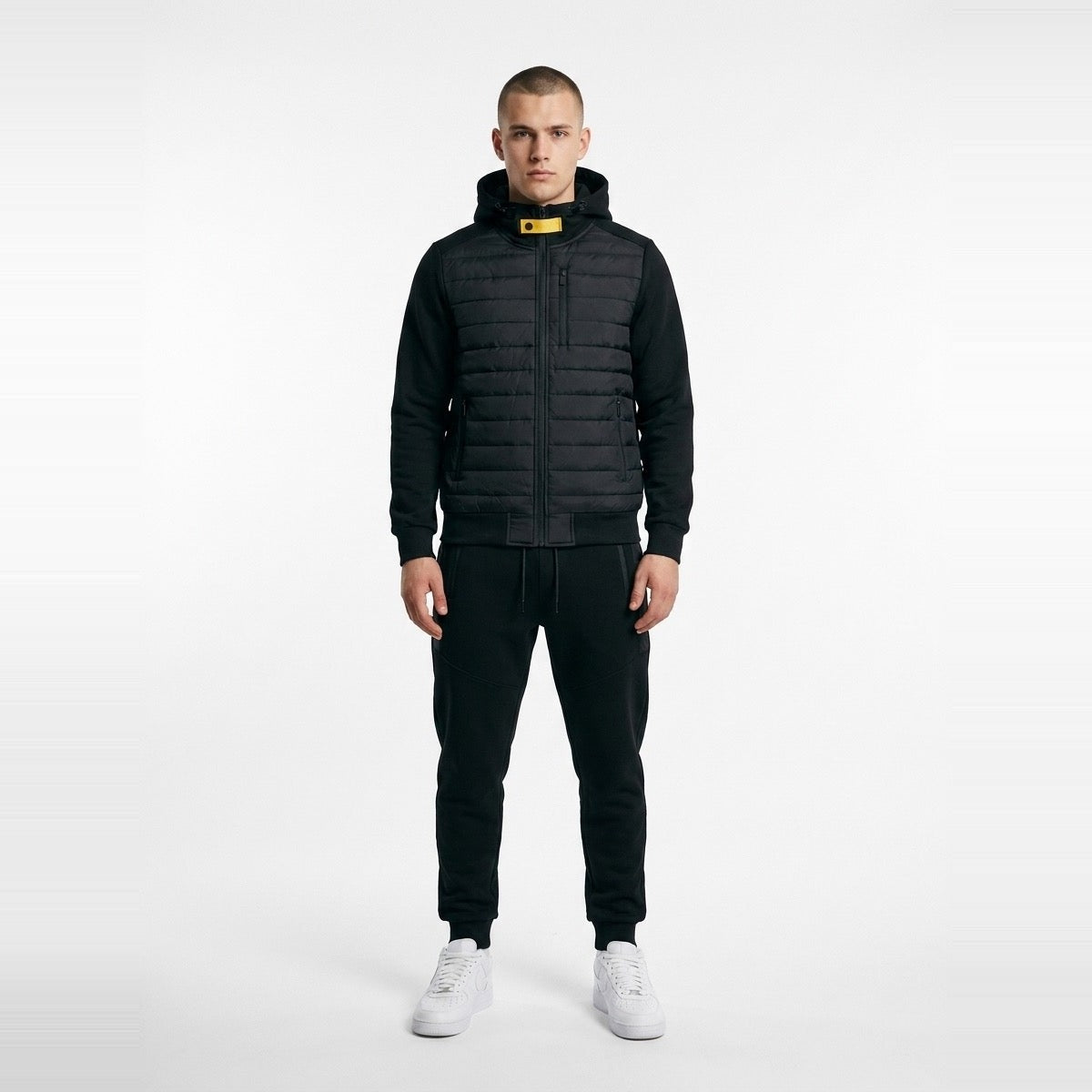 Man wearing black quilted hooded jacket with matching joggers and white sneakers | Chaps London