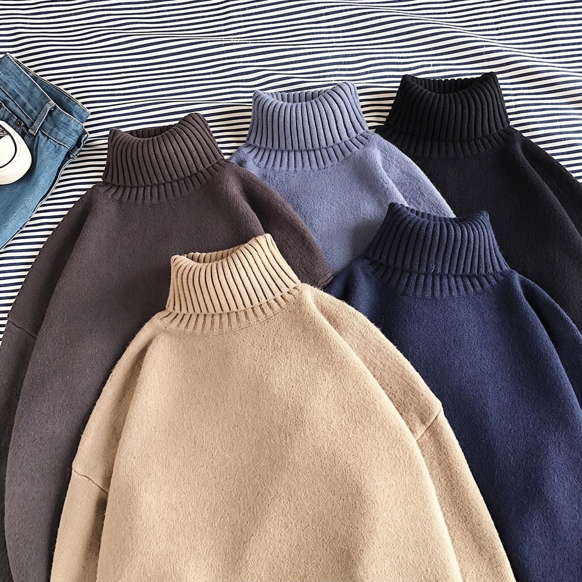 Five oversized turtleneck knit sweaters in assorted solid colors, laid flat | Chaps London